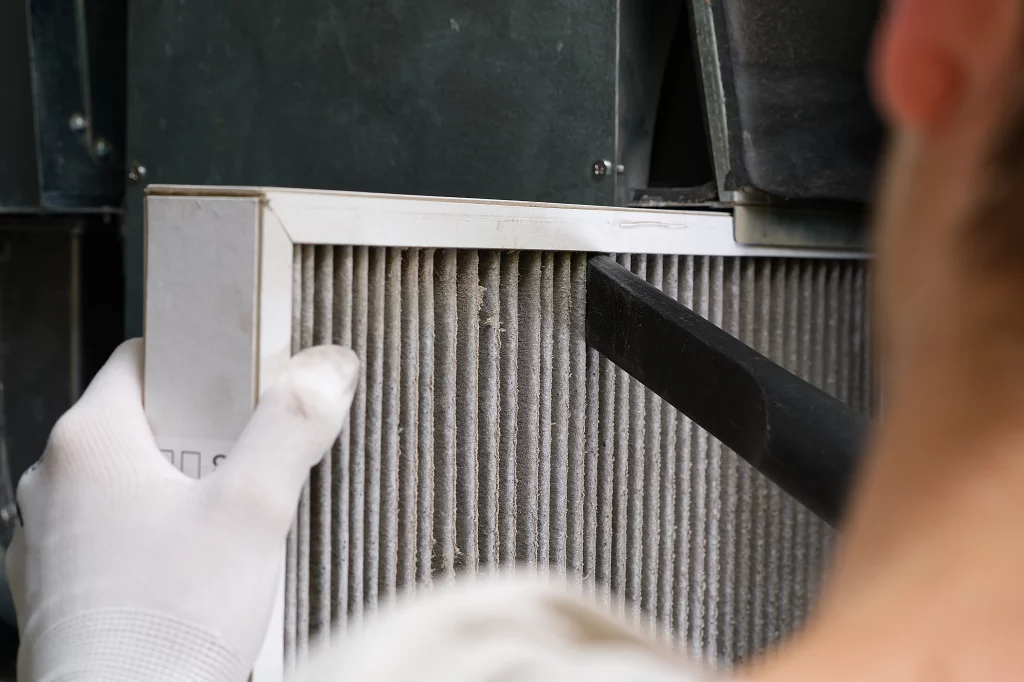 An HVAC technician cleaning out the air filters during a furnace repair